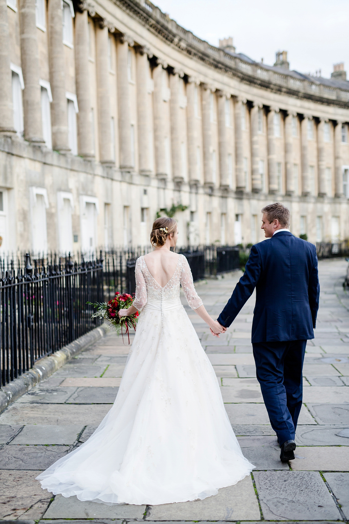 Katy wore a gold embroidered gown by Ronald Joyce for her glamorous winter wedding at Bath Assembly Rooms. Her bridesmaids wore navy blue. Photography by Lydia Stamps.