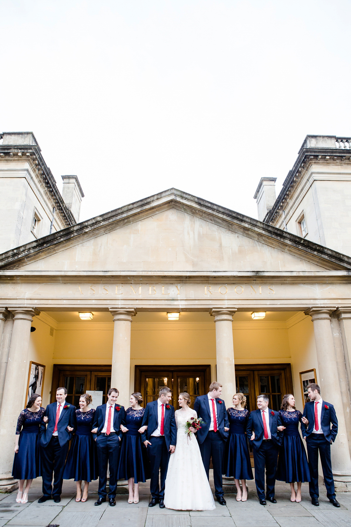 Katy wore a gold embroidered gown by Ronald Joyce for her glamorous winter wedding at Bath Assembly Rooms. Her bridesmaids wore navy blue. Photography by Lydia Stamps.