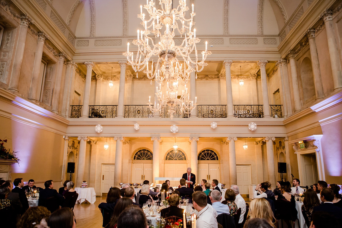 Katy wore a gold embroidered gown by Ronald Joyce for her glamorous winter wedding at Bath Assembly Rooms. Her bridesmaids wore navy blue. Photography by Lydia Stamps.