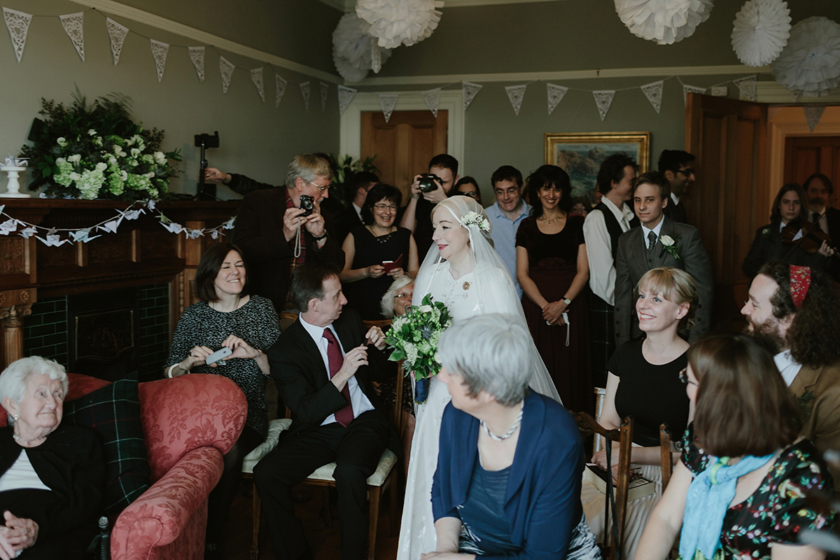 Berenice wore a 1930's vintage wedding dress for her intimate wedding held at home. The couple's ceremony involved a traditional Celtic handfasting. Photography by Rooftop Mosaic.