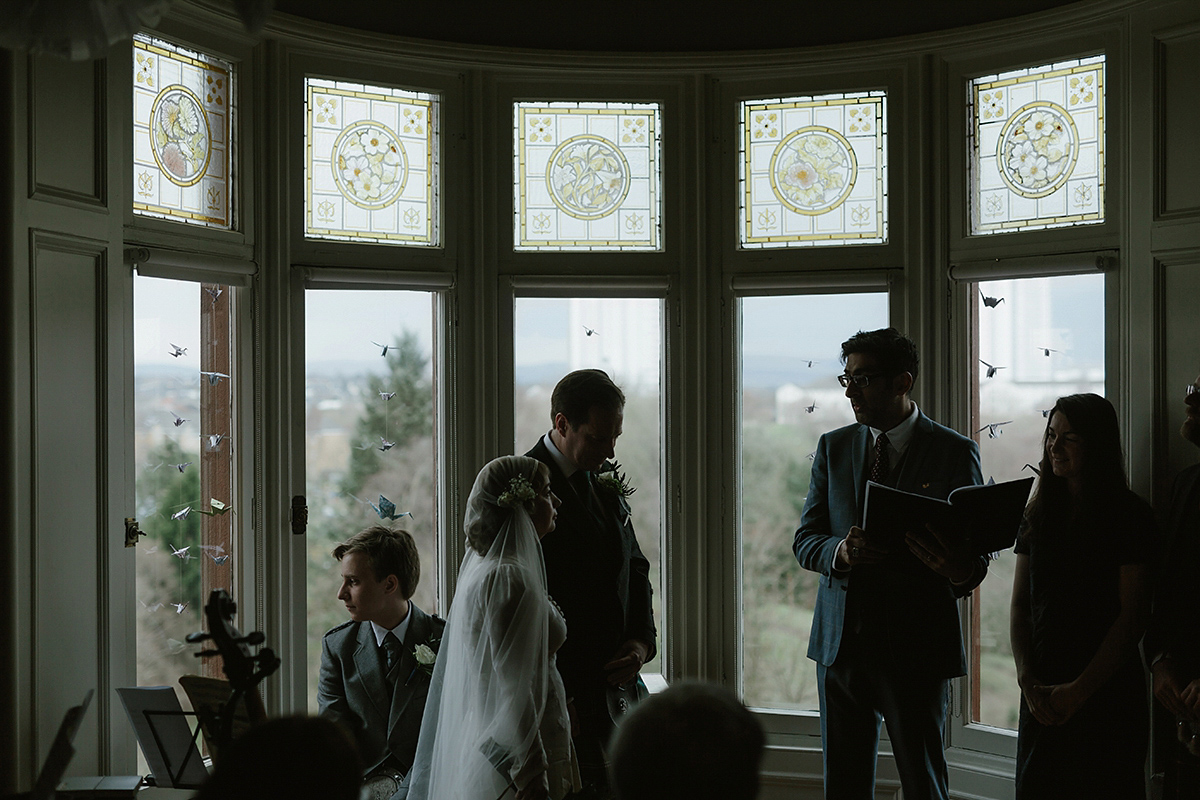 Berenice wore a 1930's vintage wedding dress for her intimate wedding held at home. The couple's ceremony involved a traditional Celtic handfasting. Photography by Rooftop Mosaic.