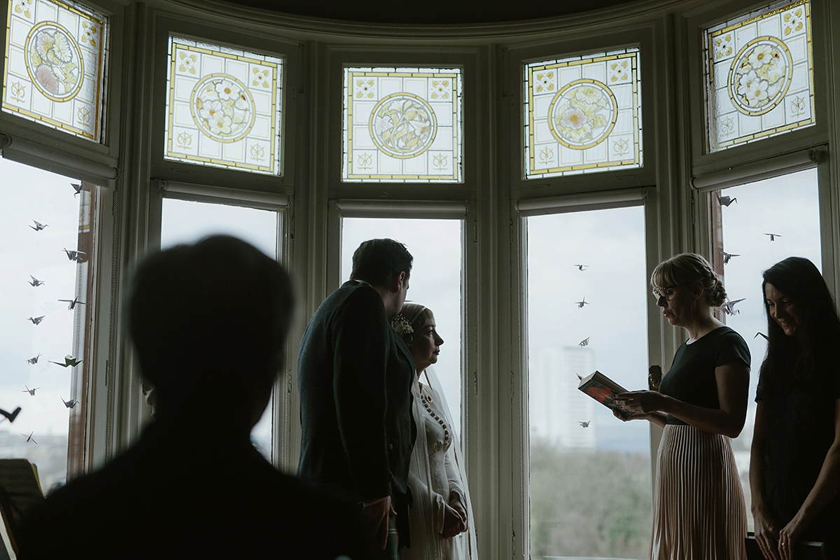 Berenice wore a 1930's vintage wedding dress for her intimate wedding held at home. The couple's ceremony involved a traditional Celtic handfasting. Photography by Rooftop Mosaic.