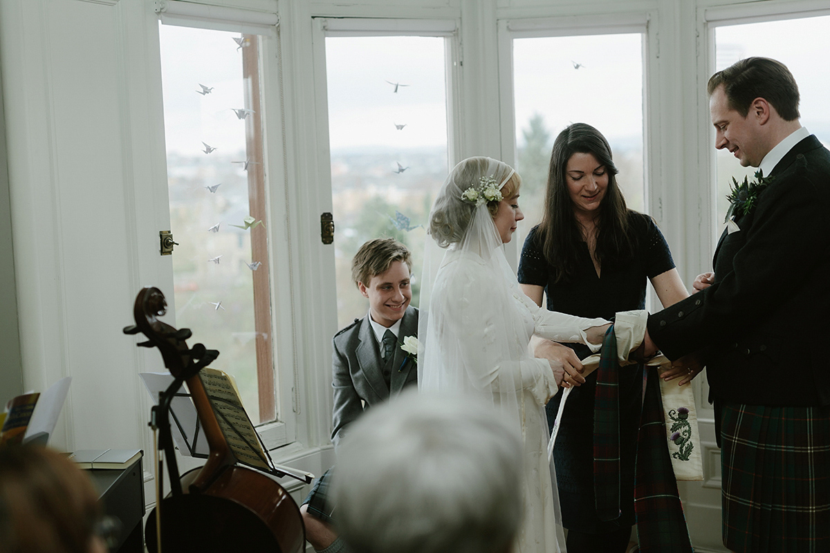 Berenice wore a 1930's vintage wedding dress for her intimate wedding held at home. The couple's ceremony involved a traditional Celtic handfasting. Photography by Rooftop Mosaic.