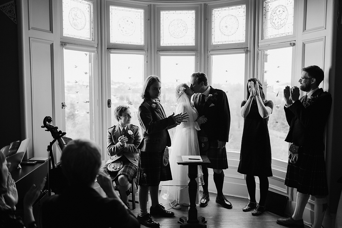 Berenice wore a 1930's vintage wedding dress for her intimate wedding held at home. The couple's ceremony involved a traditional Celtic handfasting. Photography by Rooftop Mosaic.