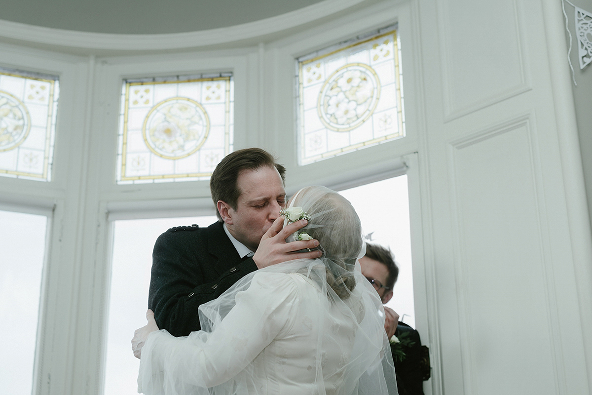 Berenice wore a 1930's vintage wedding dress for her intimate wedding held at home. The couple's ceremony involved a traditional Celtic handfasting. Photography by Rooftop Mosaic.