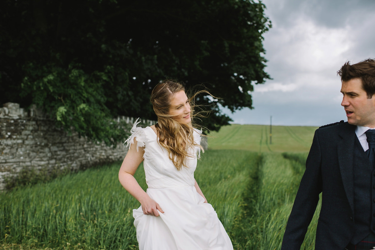 Saskia wore a Halfpenny London gown with feathered sleeves for her nature inspired wedding in Scotland. Photography by Lisa Devine.