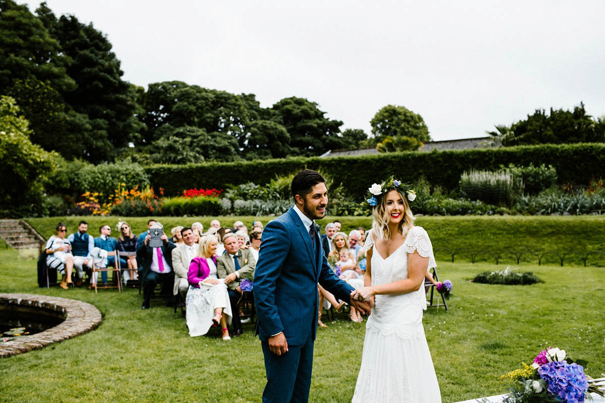 Kirsty wore a Rue de Seine gown from Leonie C. Bridal boutique in Brighton. Her handmade, Summer wedding took place in a Game of Thrones venue in Downpatrick. It was filled with floral chandeliers. Photography by Honey and the Moon.