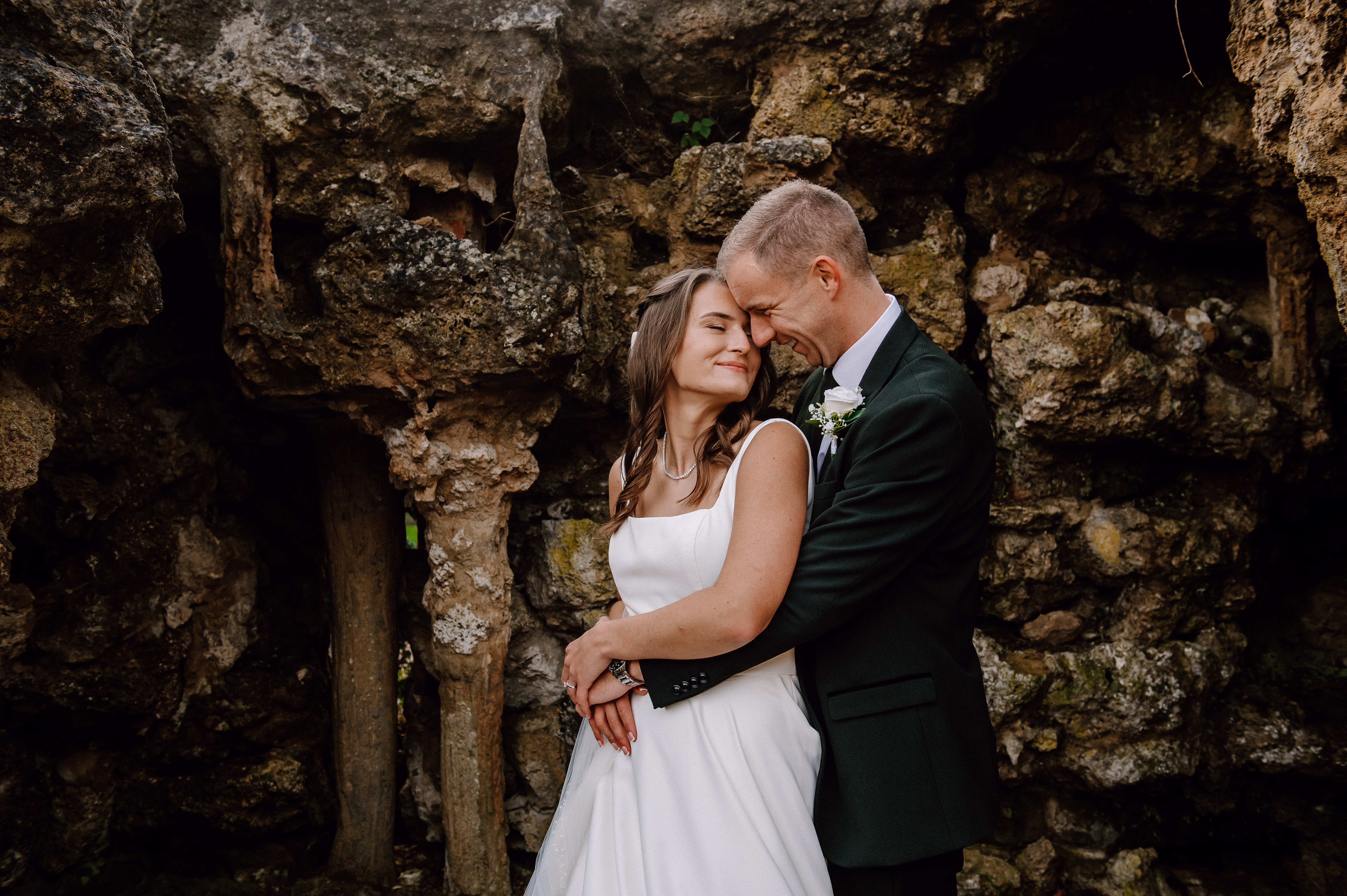 Couple cuddle together amongst rugged rocks.