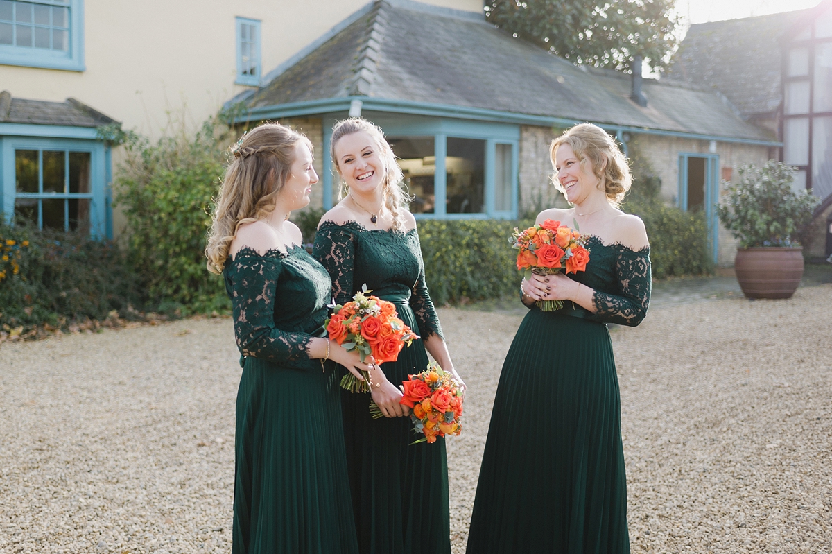 20 Bridesmaids in pleated bottle green dresses by Coast with orange Autumn wedding bouquets