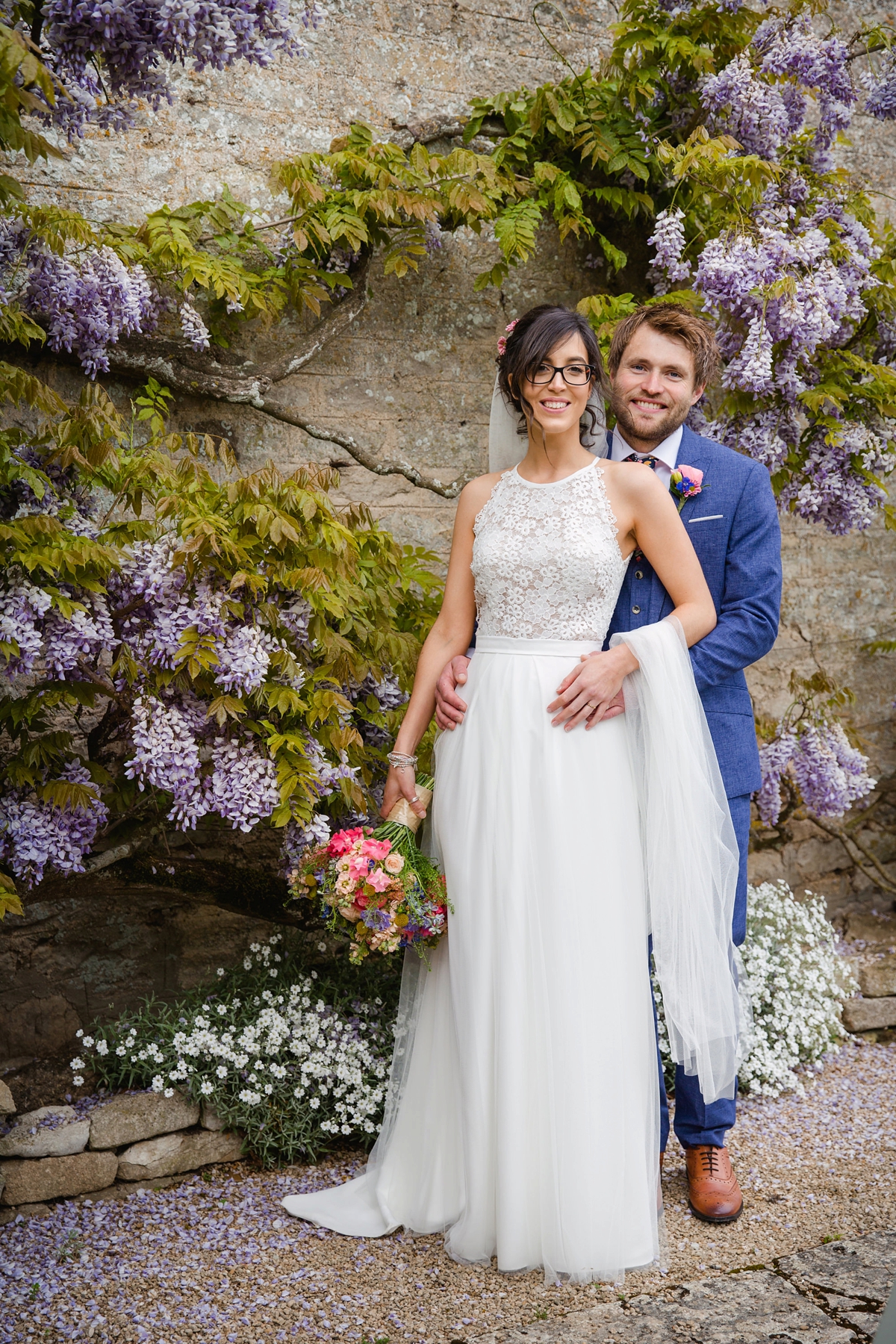 24 Bride and groom standing in front of a Wisteria backdrop 1