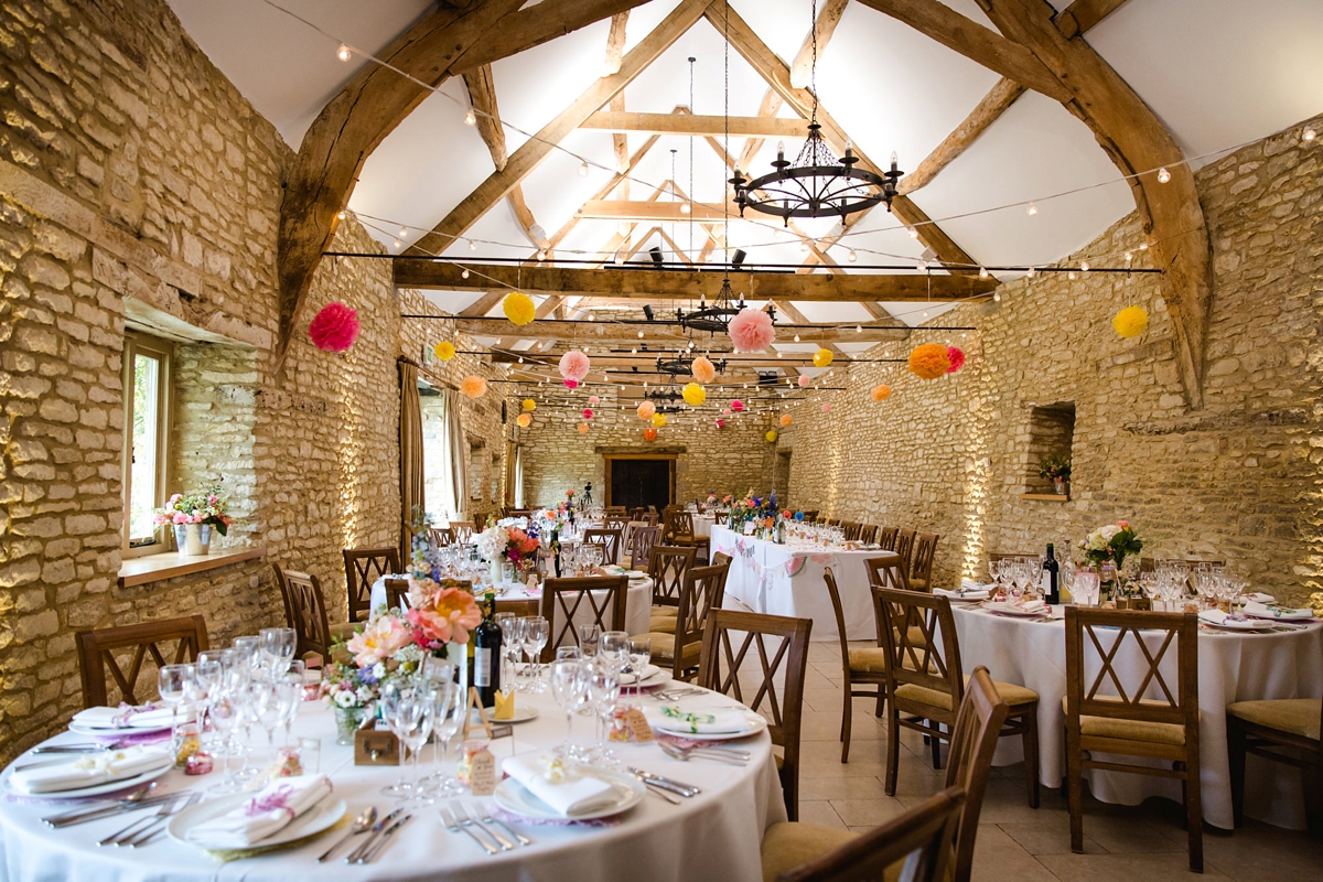 29 Colourful paper pompoms hanging from the ceiling of a barn wedding venue 1