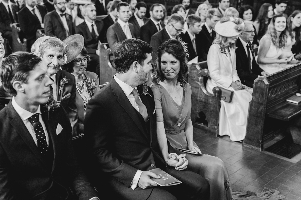 3 Black and white image of couple sat in church during their wedding ceremony