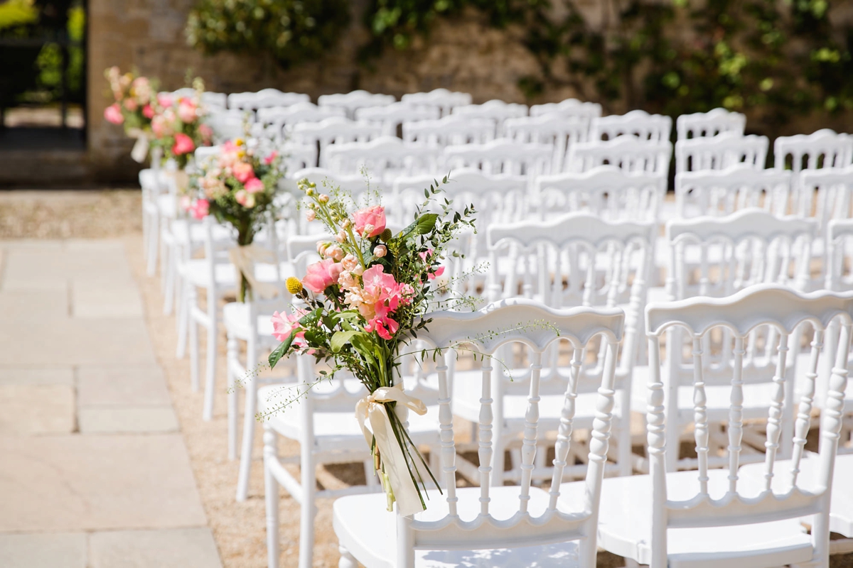 3 Outdoor wedding ceremony with bouquets tied to white chairs 1