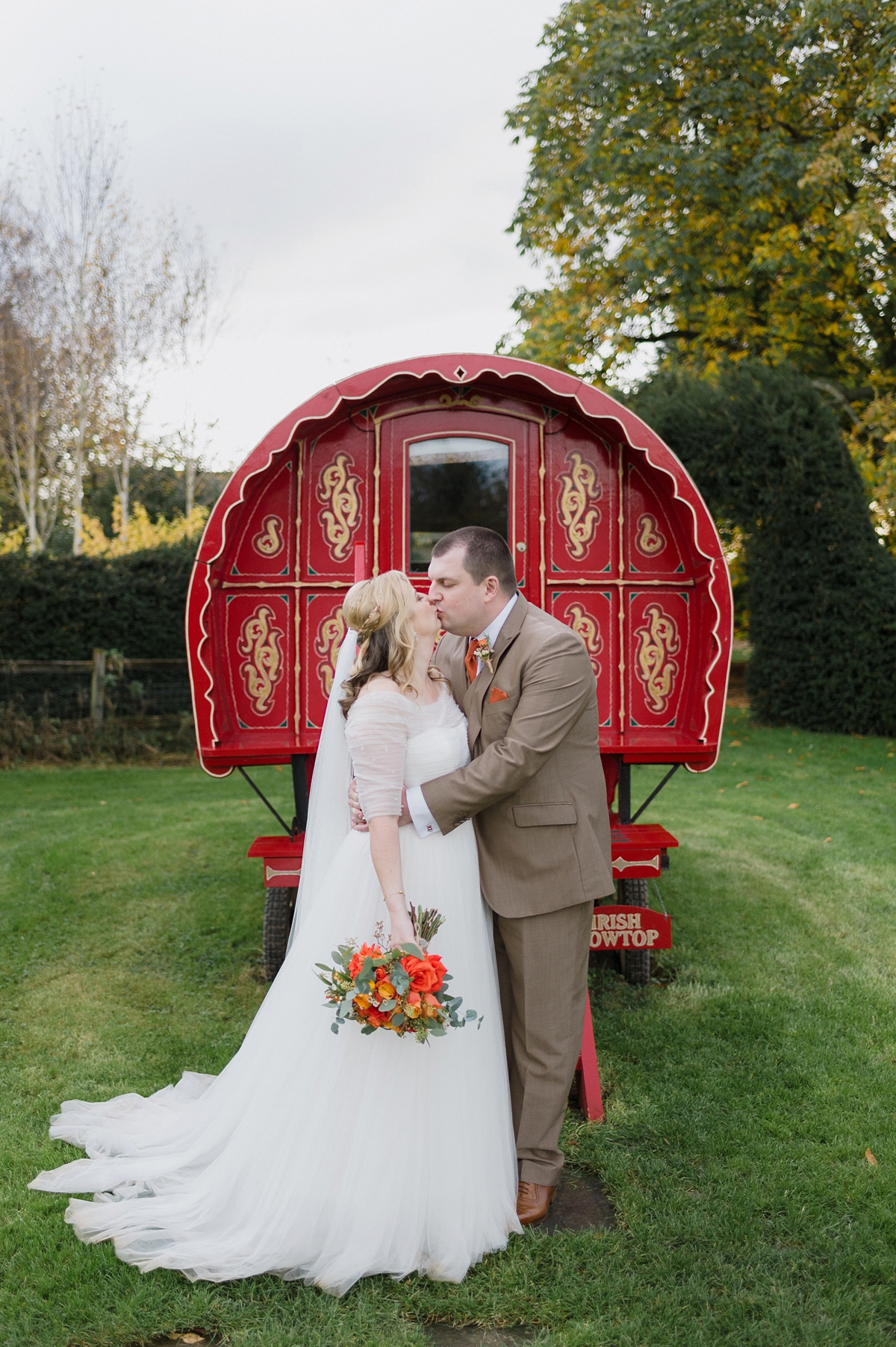 32 Bride and groom standing by a red gypsy caravan