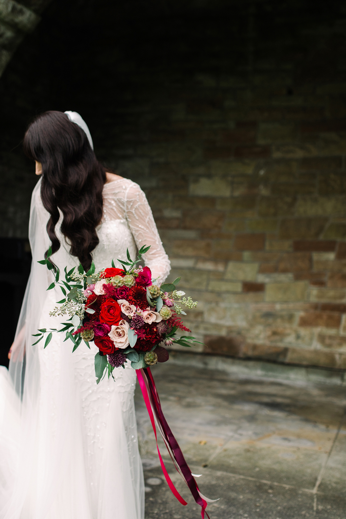 33 Bride with long dark wavy hair wearing Rosa Clara and carrying a red wedding bouquet
