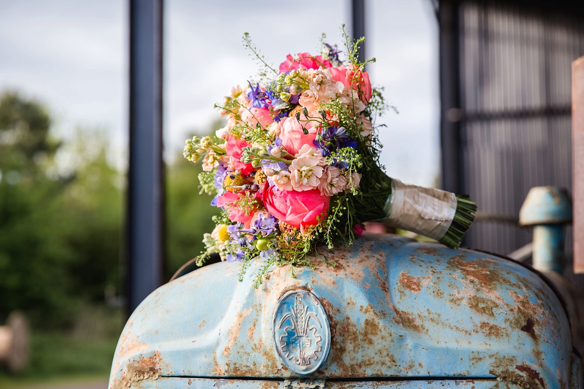 37 Colourful summer bouquet rested on top of a rusting tractor for a rustic barn wedding 1