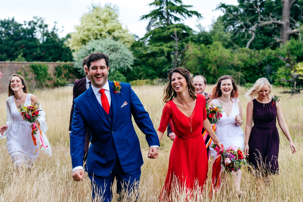 7 Bride in a red wedding dress running through a field with her groom