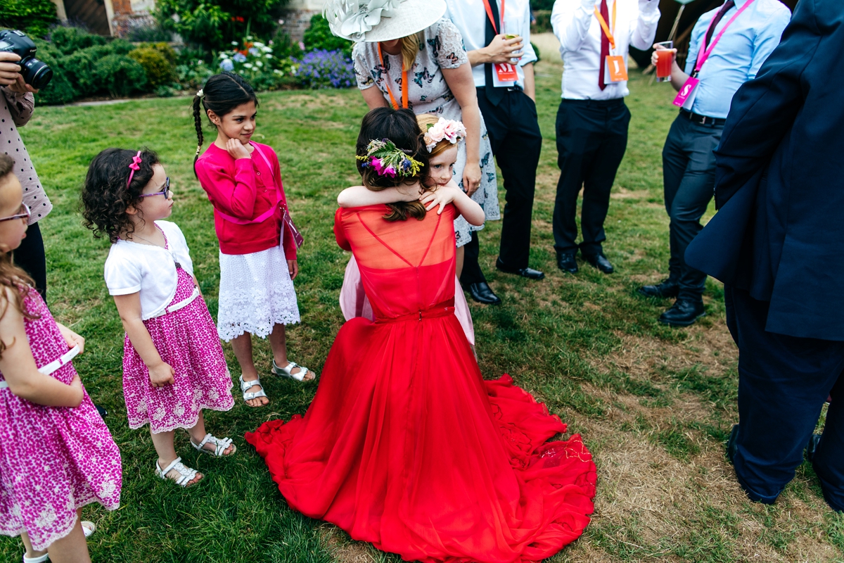 9 Bride in a red wedding dress hugging her flowergirl