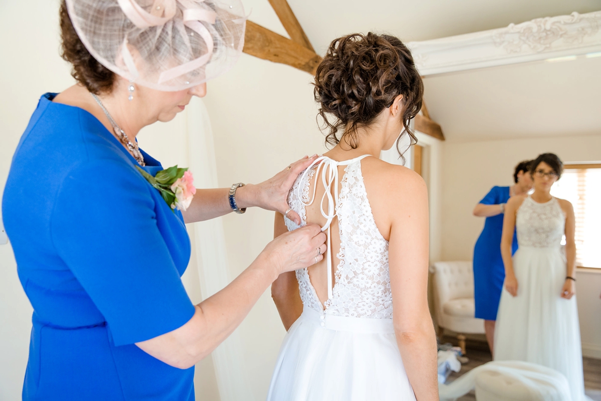 9 Mother of the bride in blue helping the bride into her wedding dress 1