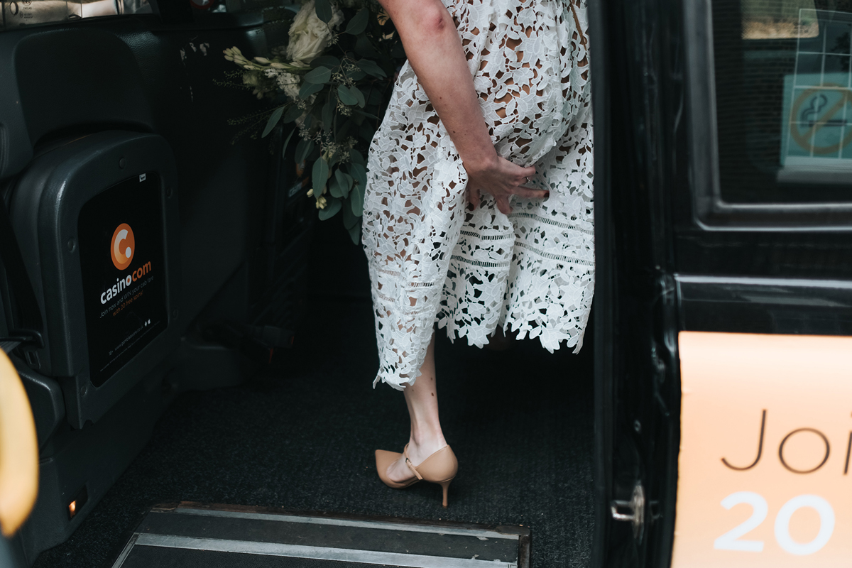 Bride getting into a London taxi cab in a Self Portrait dress and LK Bennett shoes