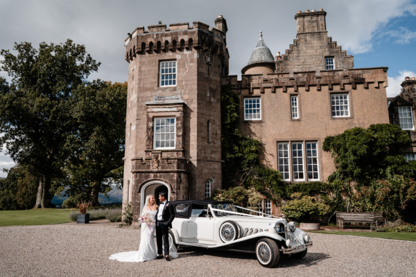 bride and groom with wedding car in front of boturich castle