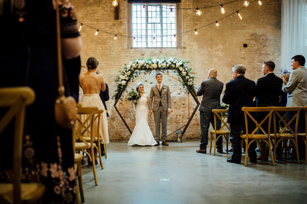 A Jesus Peiro Gown, Bridesmaids in Grey and a Floral Hexagon Ceremony Backdrop