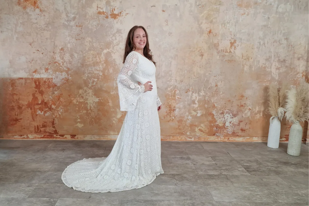 Woman wearing a retro lace wedding dress with bell sleeves.