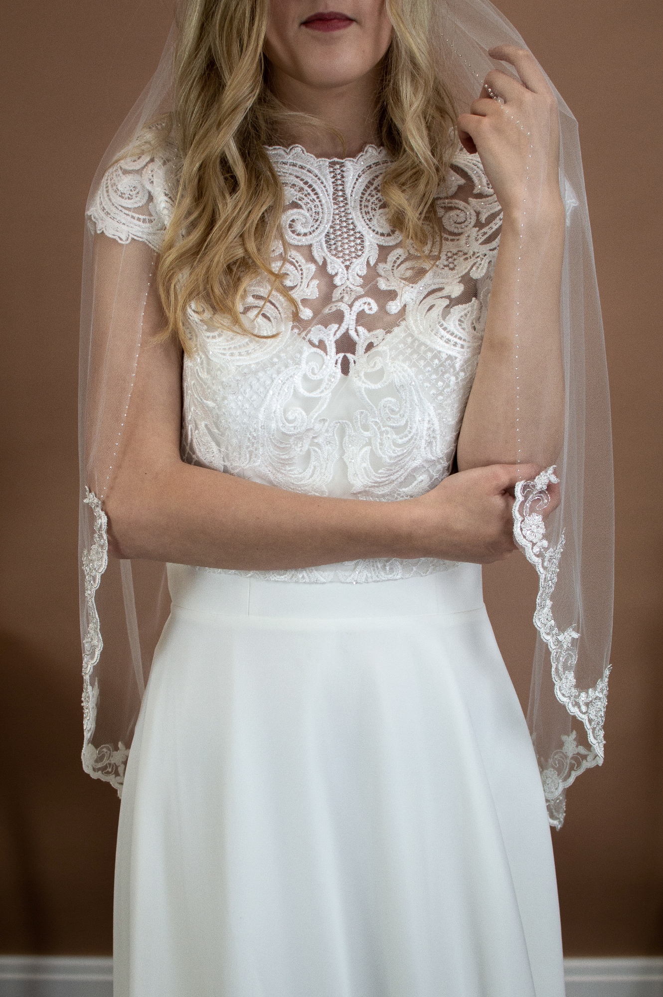 Alana single layer hip length veil with silver and ivory lace topped with a hand beaded edge on a bride font shot - The Wedding Veil Shop: Wedding Veil Lengths + Styles for Every Bride