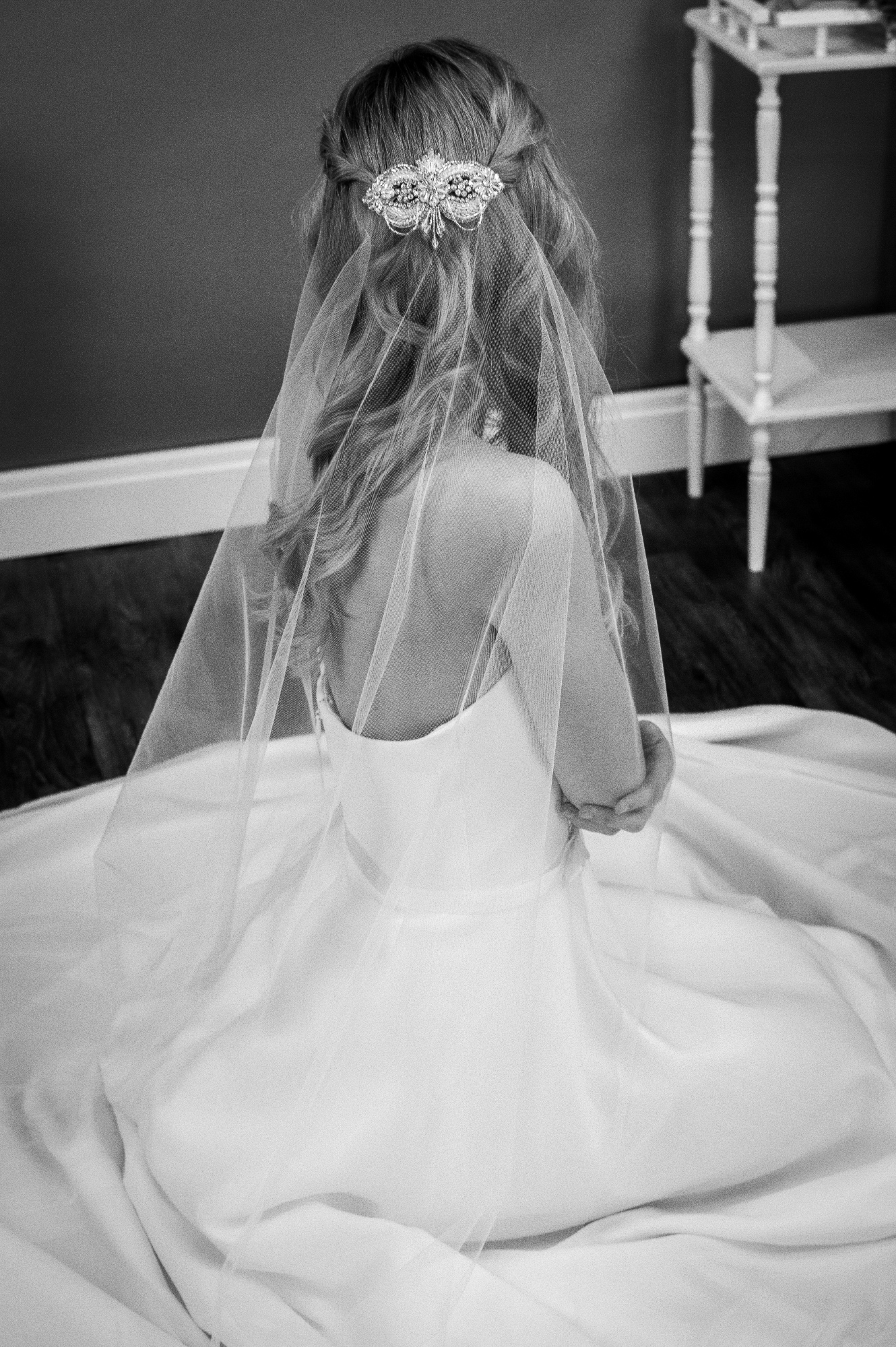 Gloria one layer chapel length barely there veil with a crystal beaded veil topper bride sitting down bw - The Wedding Veil Shop: Wedding Veil Lengths + Styles for Every Bride
