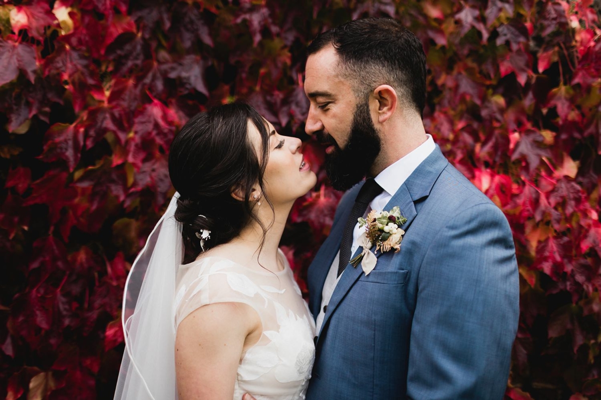 Bride and groom against a red autumnal leaf wall