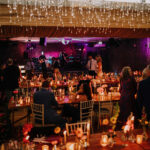 magical candlelit wedding reception with purple lighting in dance floor behind tables