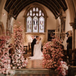 stunning wedding church wedding ceremony with pink flowers and candles in Elmore Cotswolds UK