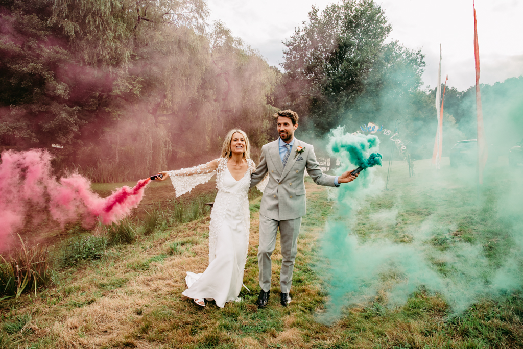 Bride and groom holding smoke grenades for couples portraits
