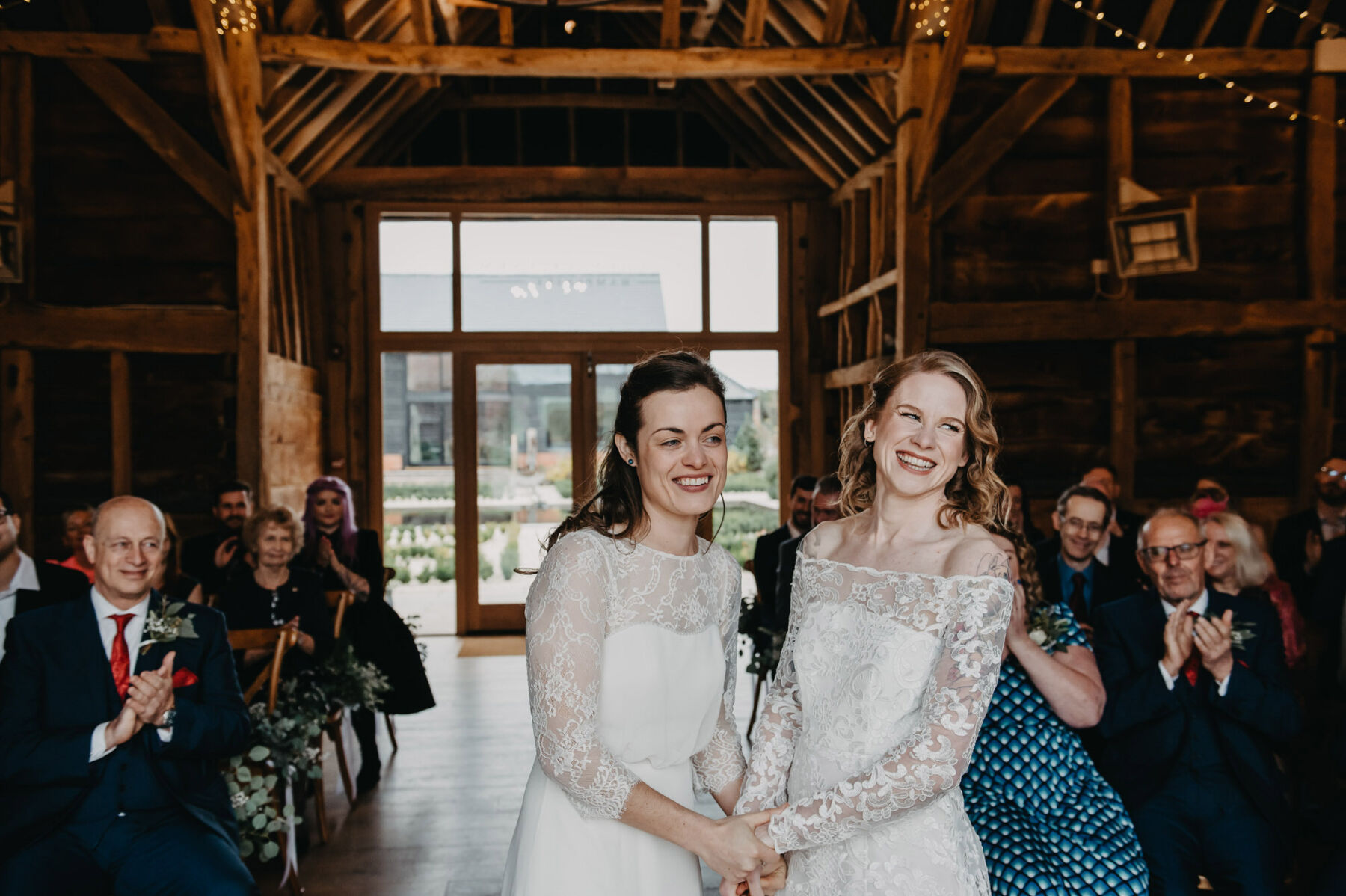 Two brides holding hands at LGBTQ+ wedding ceremony. Jessica Grace Photography.