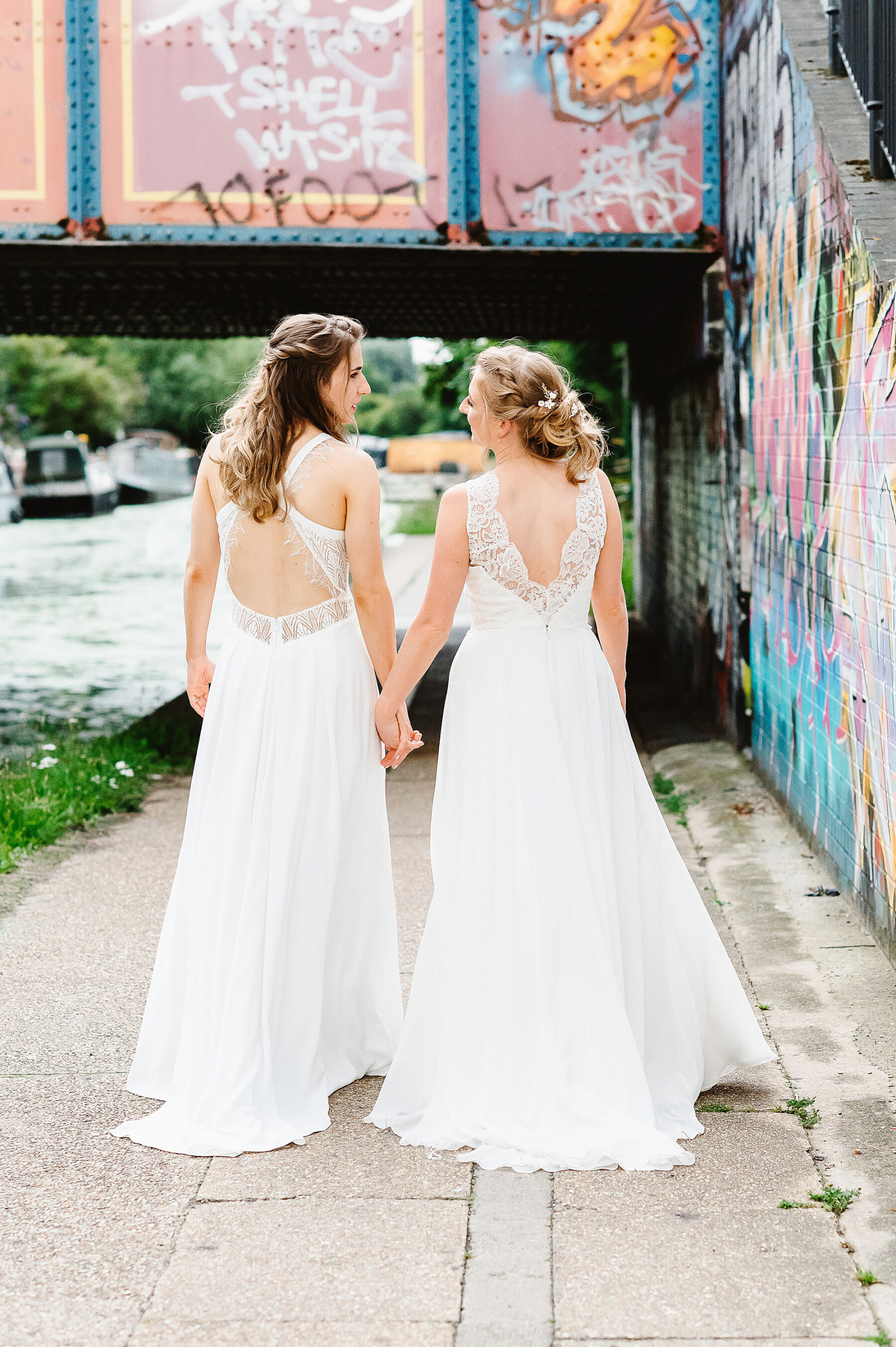 Back of two brides holding hands. LGBTQ wedding.