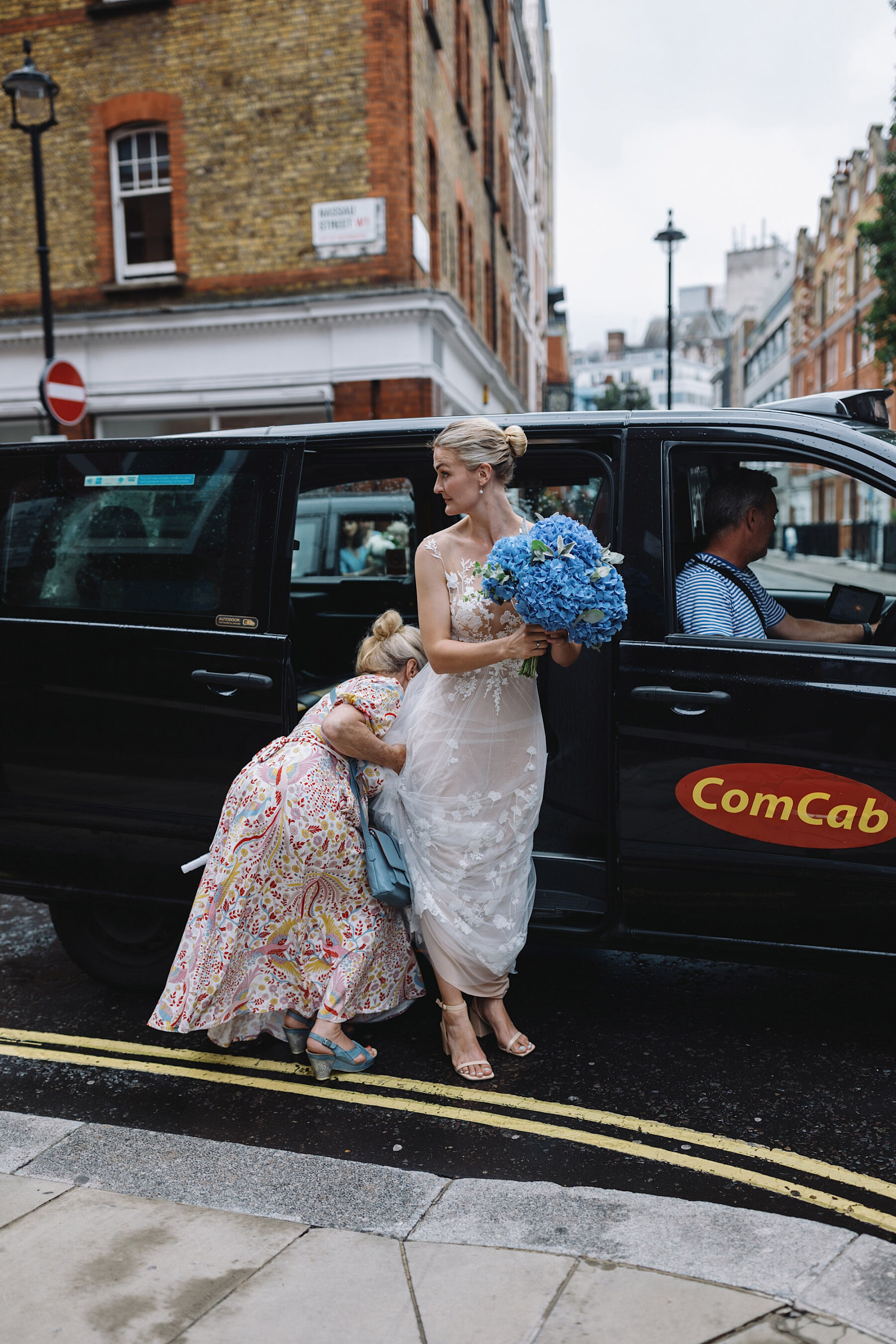 Large blue hydrangea wedding bouquet. Bride getting out of a London black cab taxi. Wolf & Co. Photography