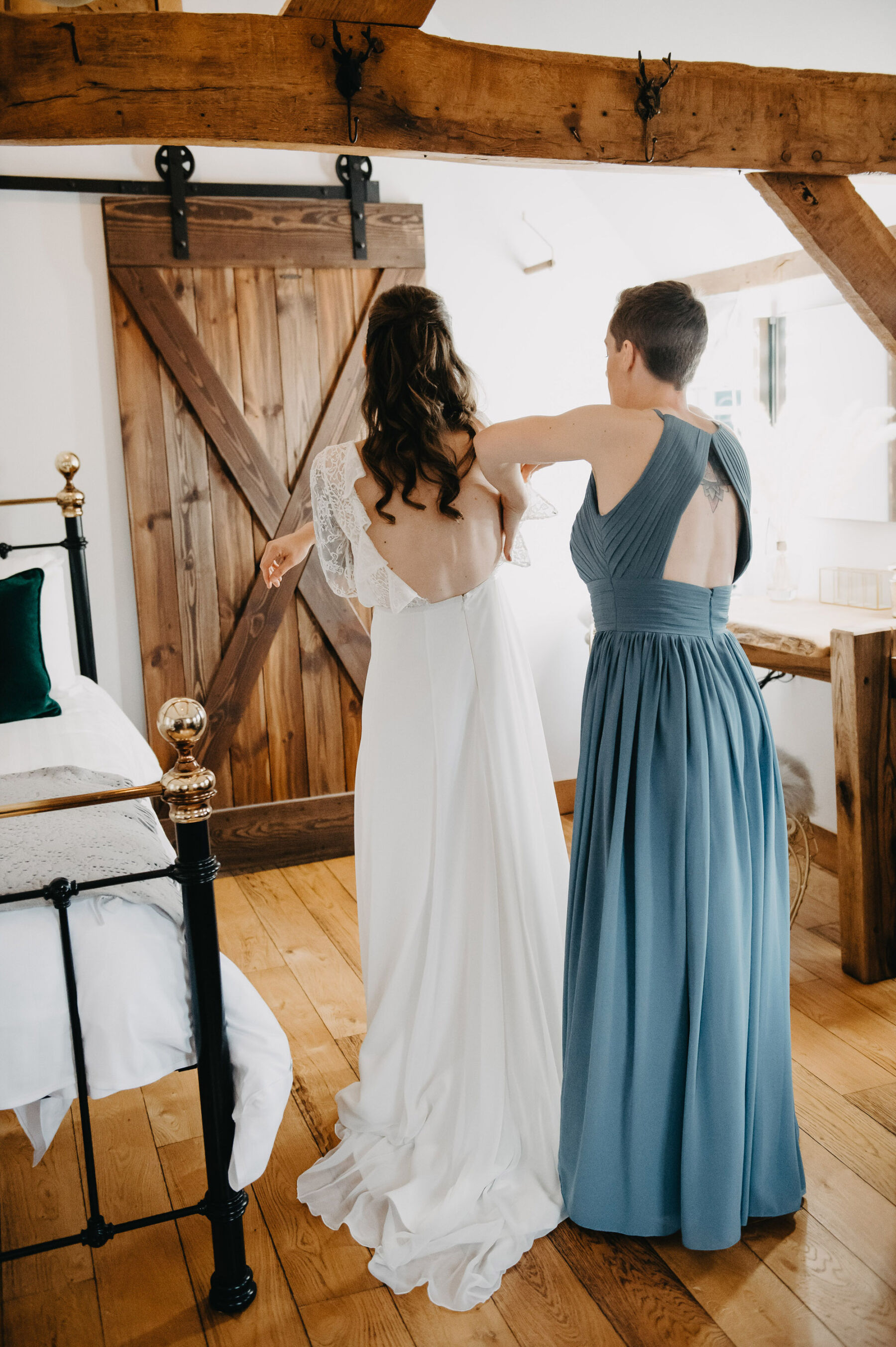 Bridesmaid assisting bride into backless lace wedding dress. Jessica Grace Photography.