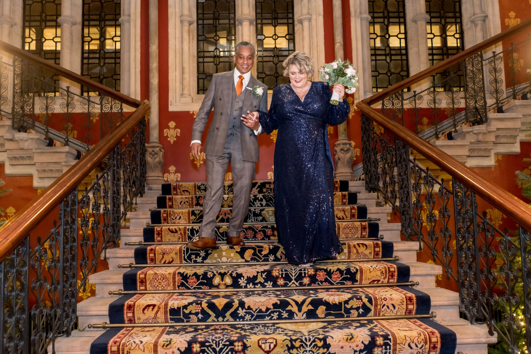 Newlywed couple standing on the stairs at the St Pancras Renaissance Hotel, London.