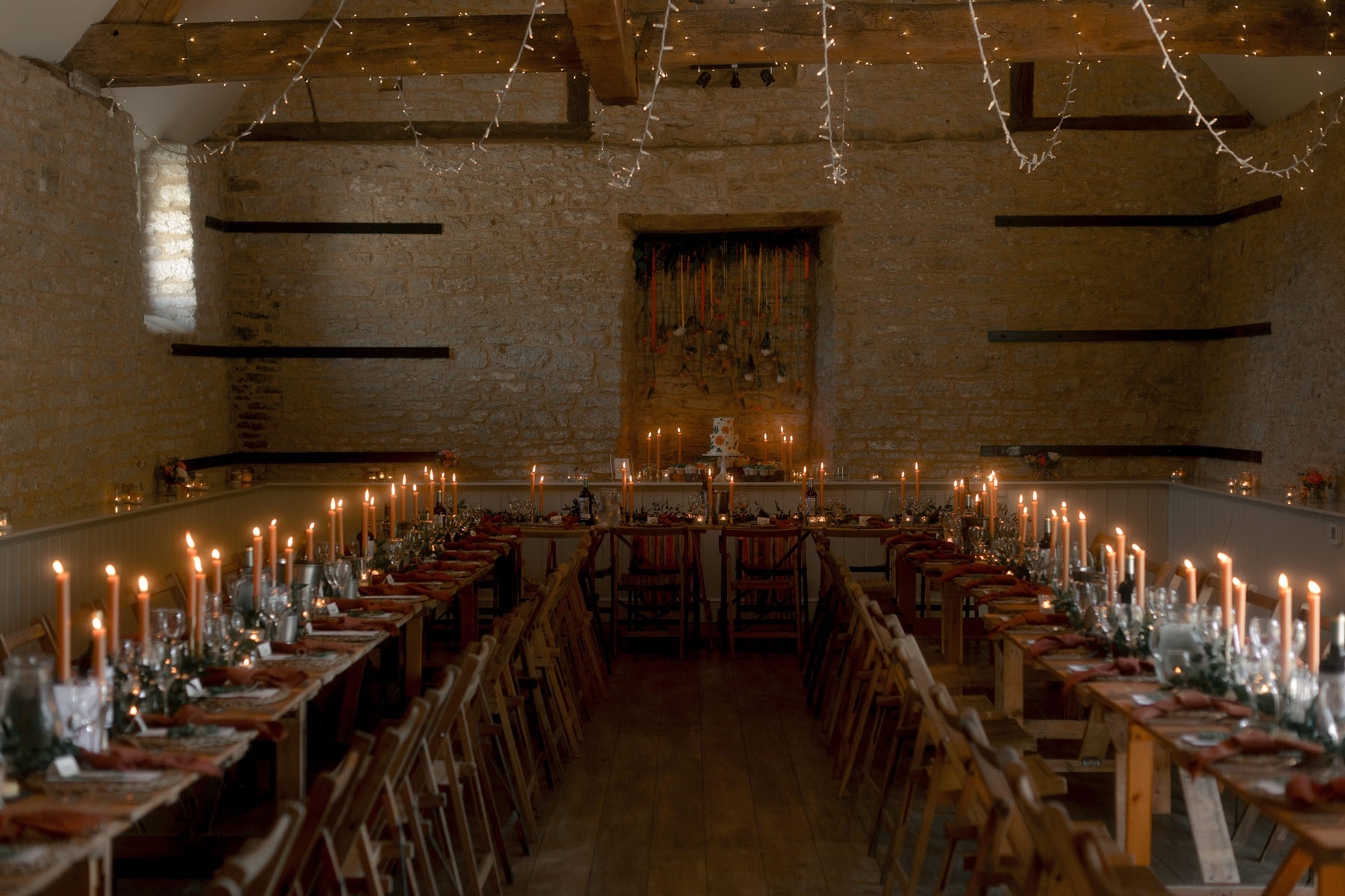Candlelit barn wedding reception with fairylight canopy hanging over the table. Wick Farm, Bath.