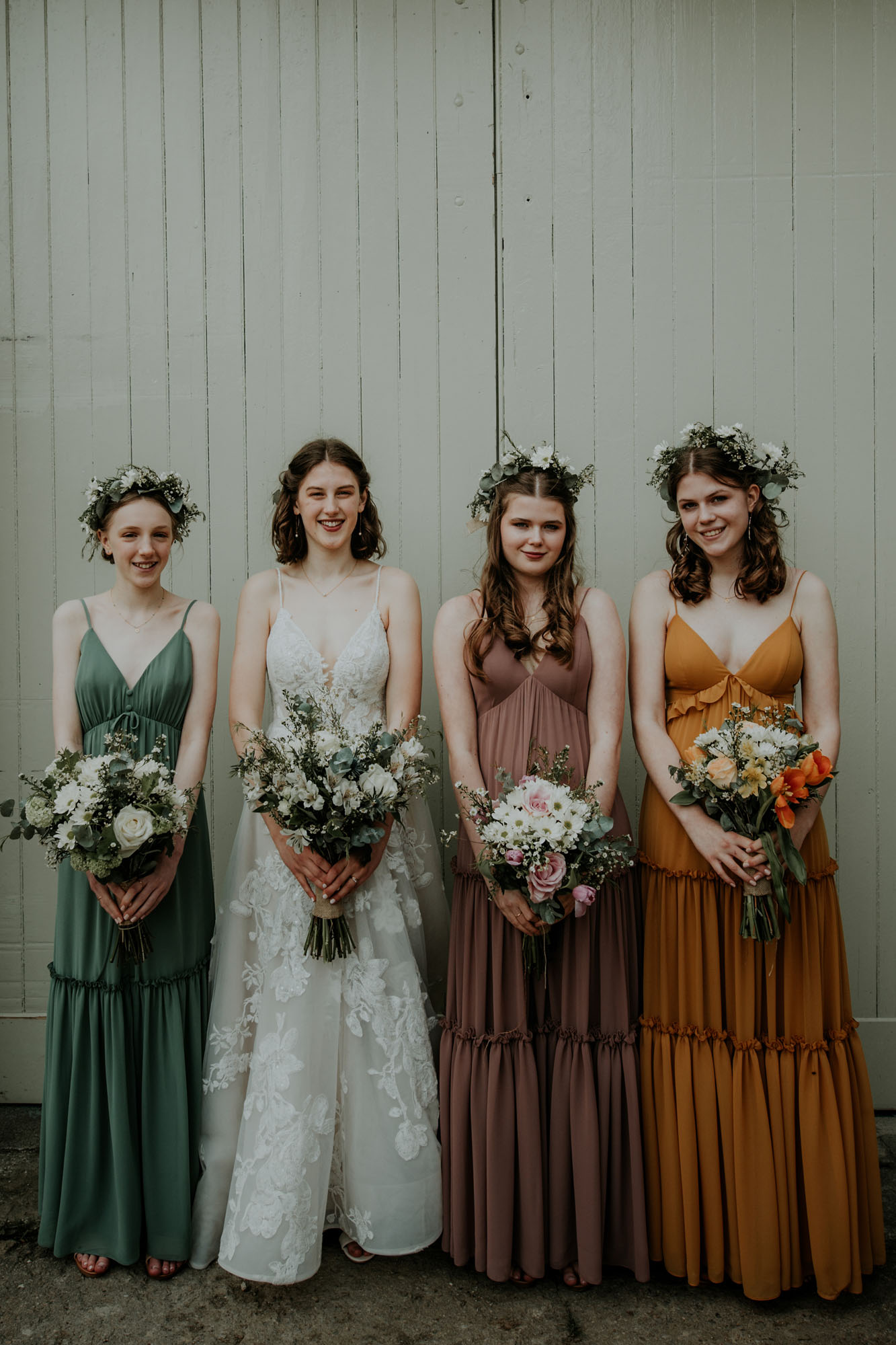 Bride standing with bridesmaids in green and ochre wedding dresses