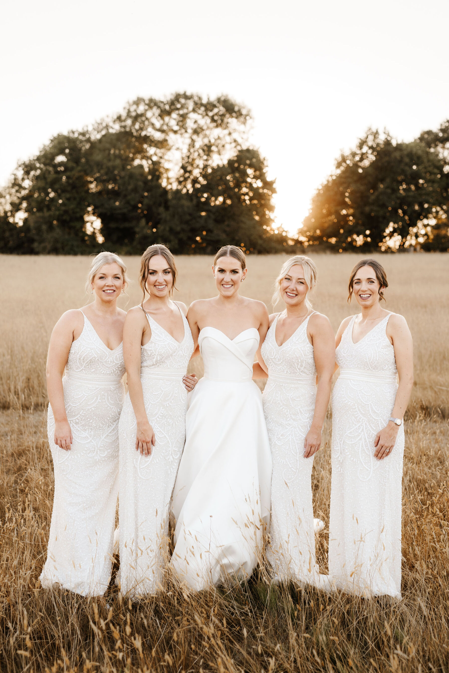 Bride in bespoke Suzanne Neville dress hugging bridesmaids in white dresses from ASOS