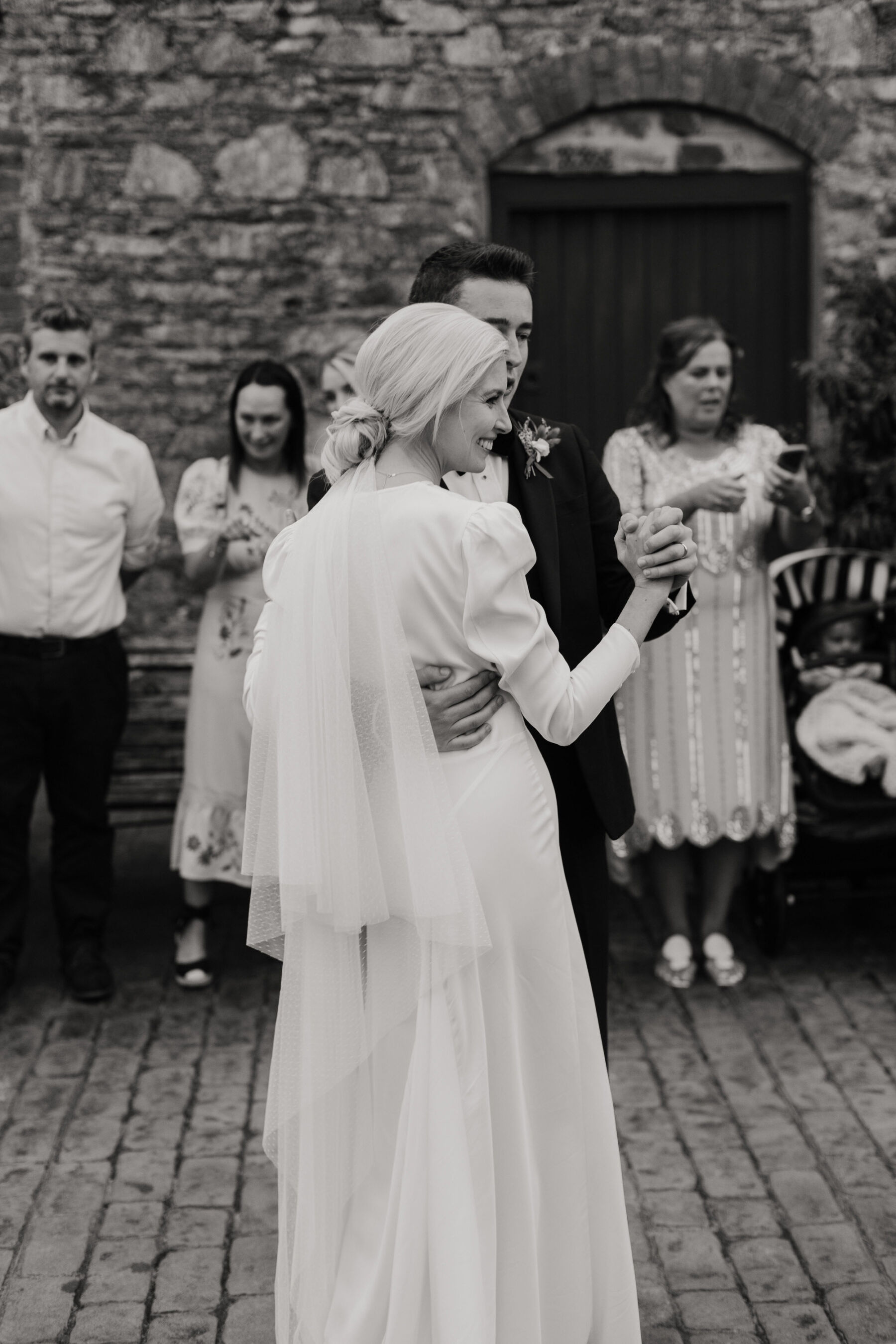 Bride in Rixo wedding dress dancing with her groom in black tie