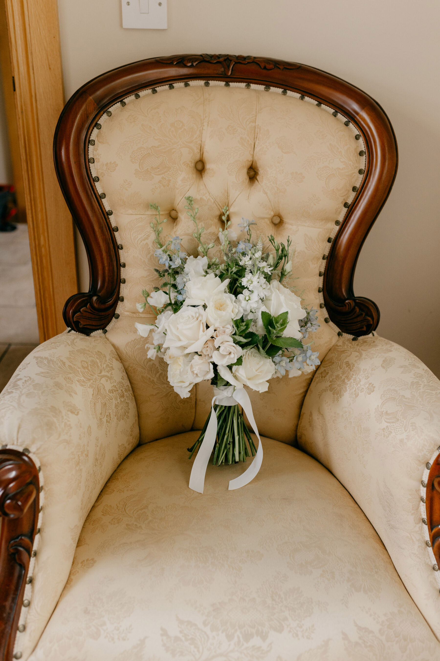 Elegant wedding bouquet of all white flowers positioned on a chair.