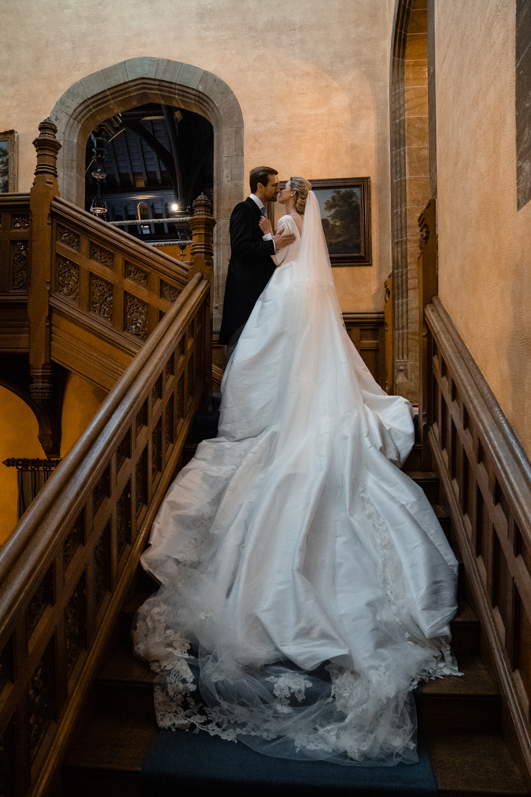 Bride in Jesus Peiro wedding dress with long train standing on stairs