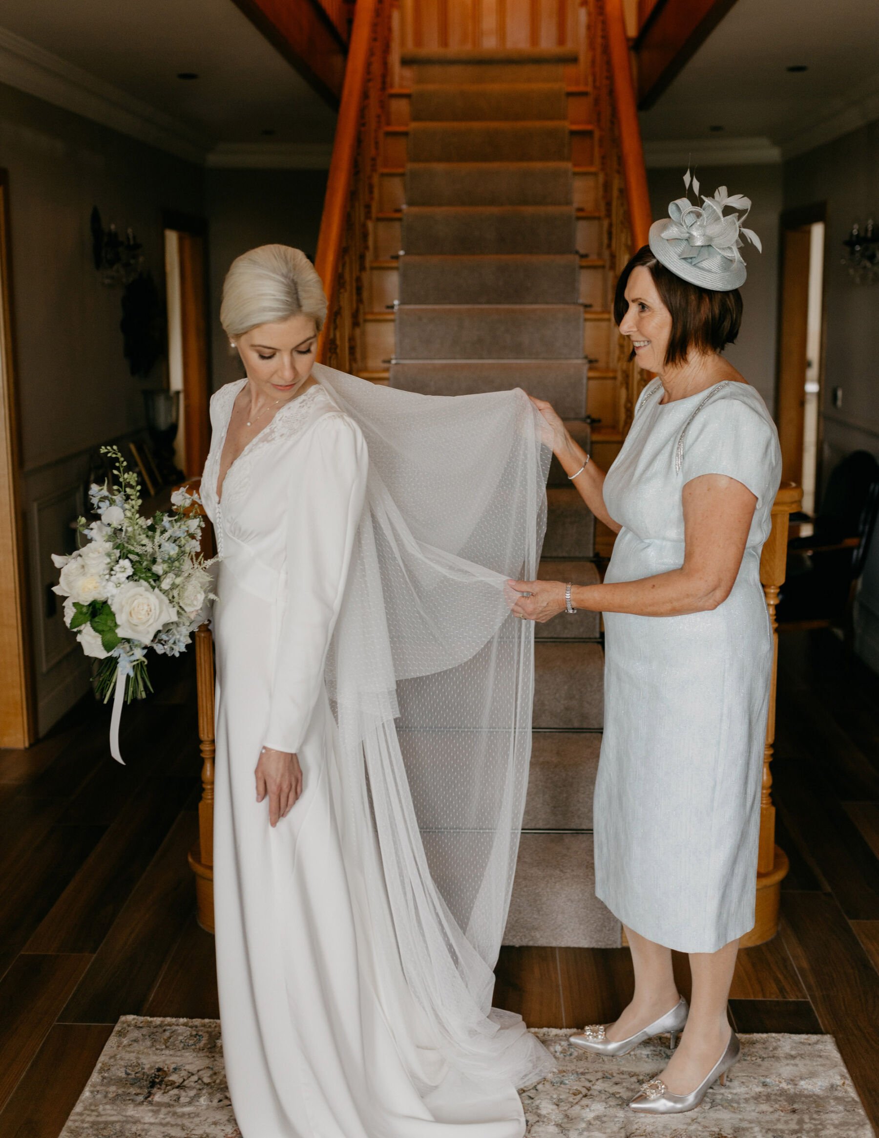 Bride in a Rixo wedding dress and veil - mother of the bride lifting the veil.