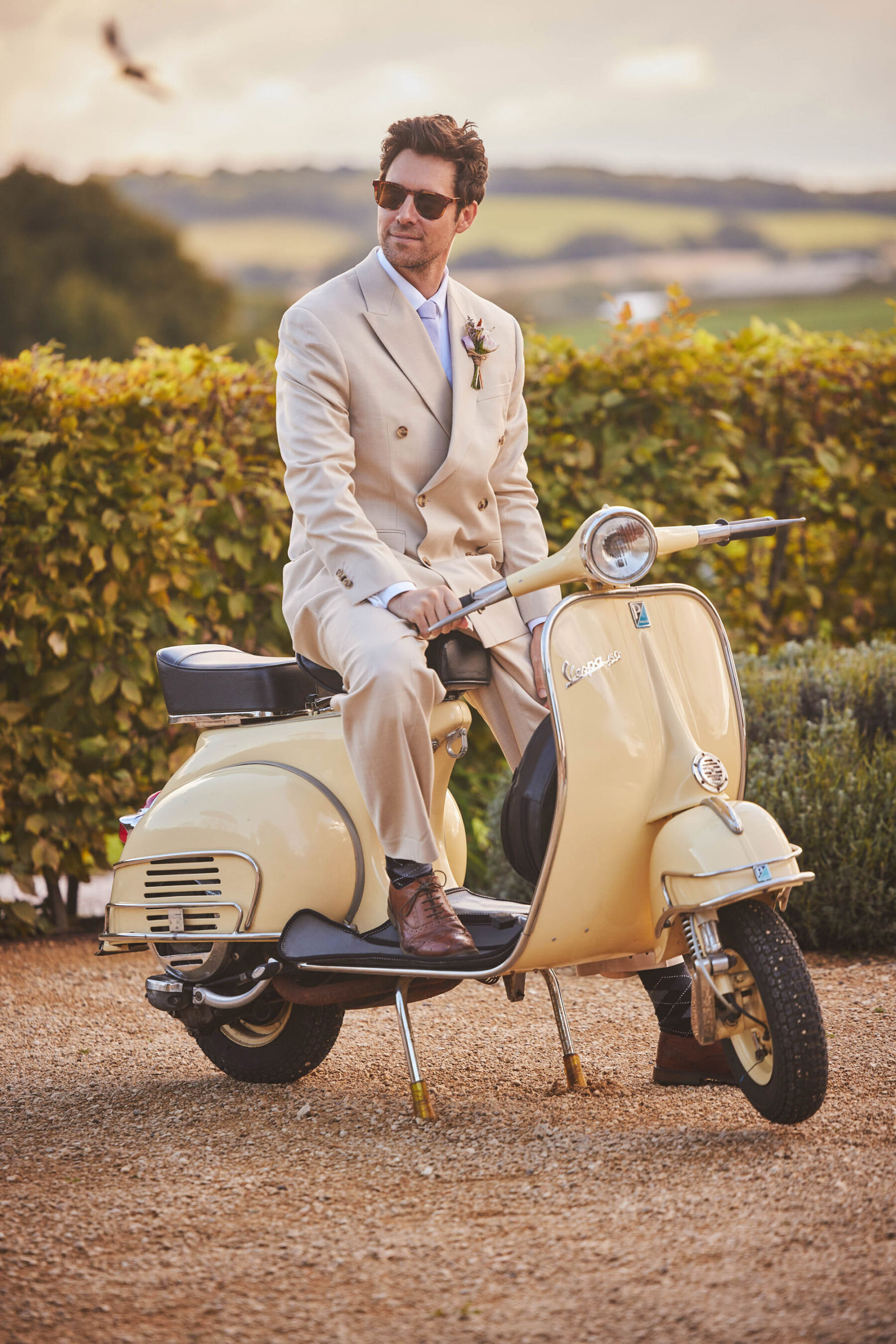 Groom on pale yellow Vespa at Brickhouse Vineyard - Devon wedding venue.