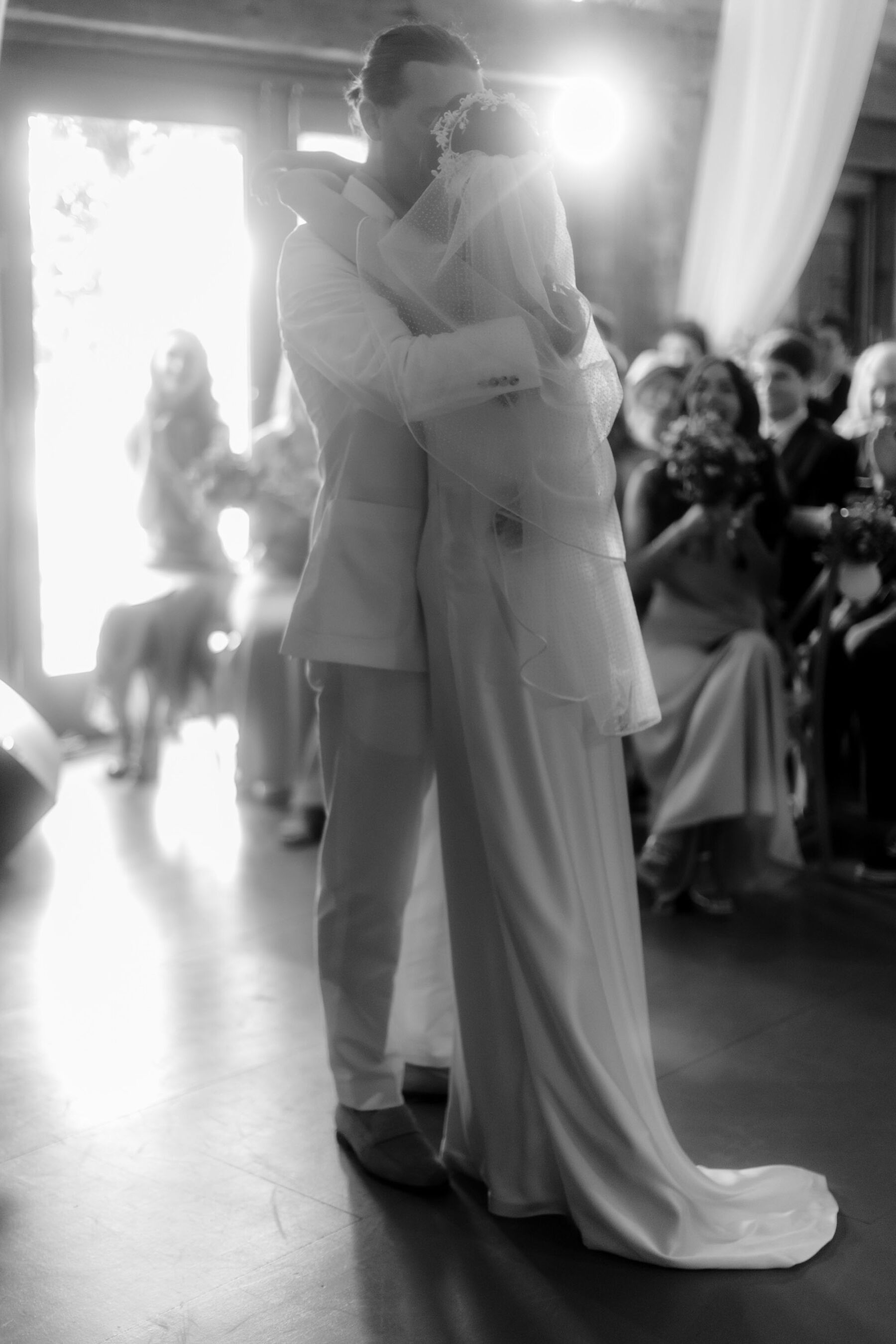 Black and white shot of bride and groom embracing.