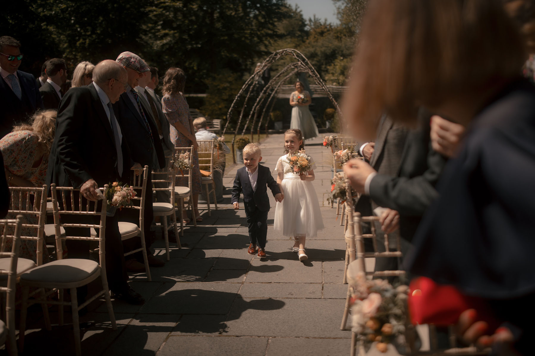 Sweet little flowergirl and page boy holding hands whilst walking down the aisle.