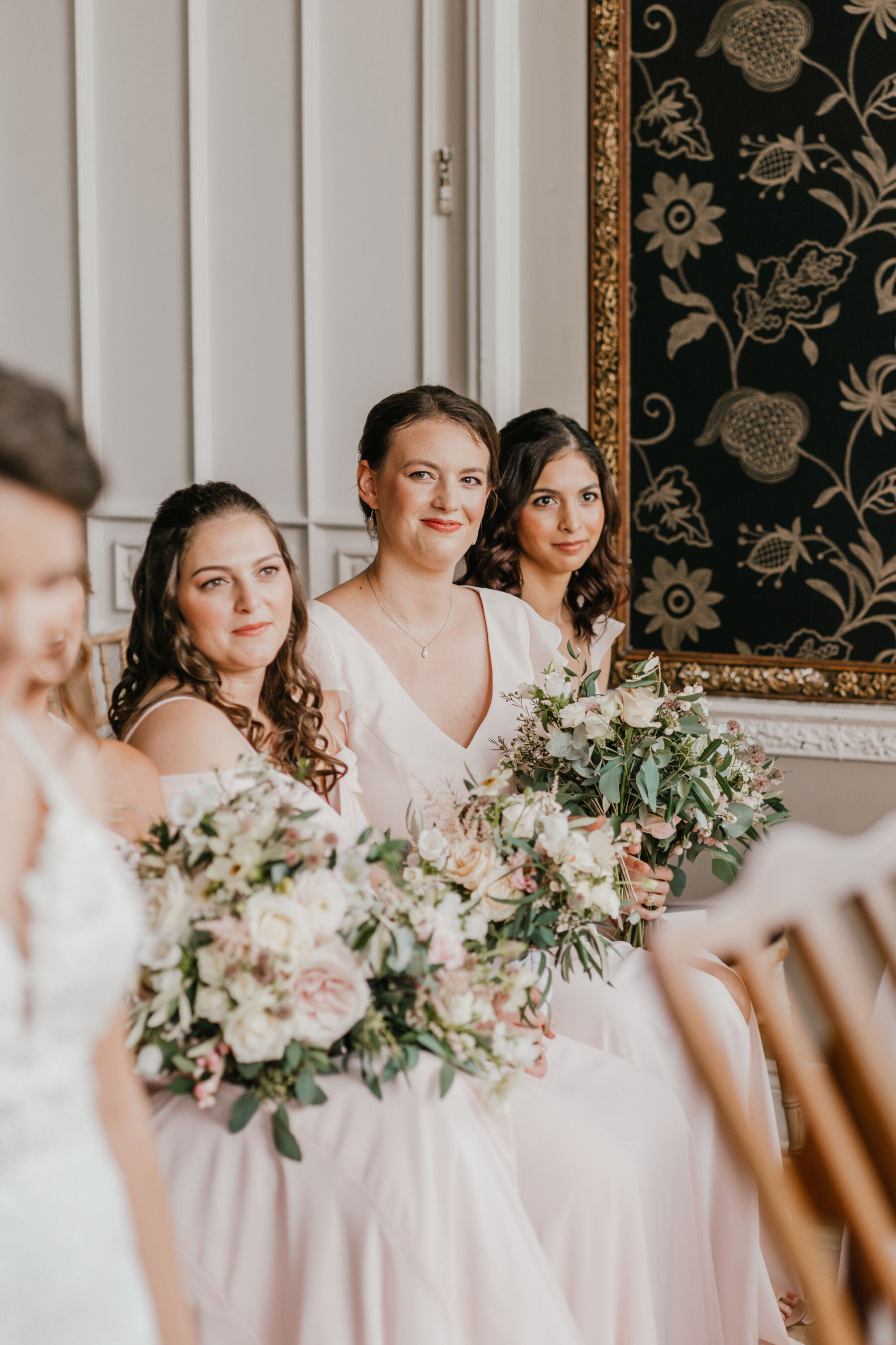 Bridesmaids seated during a wedding ceremony at Nonsuch Mansion, Surrey. Shelby Ellis Photography.