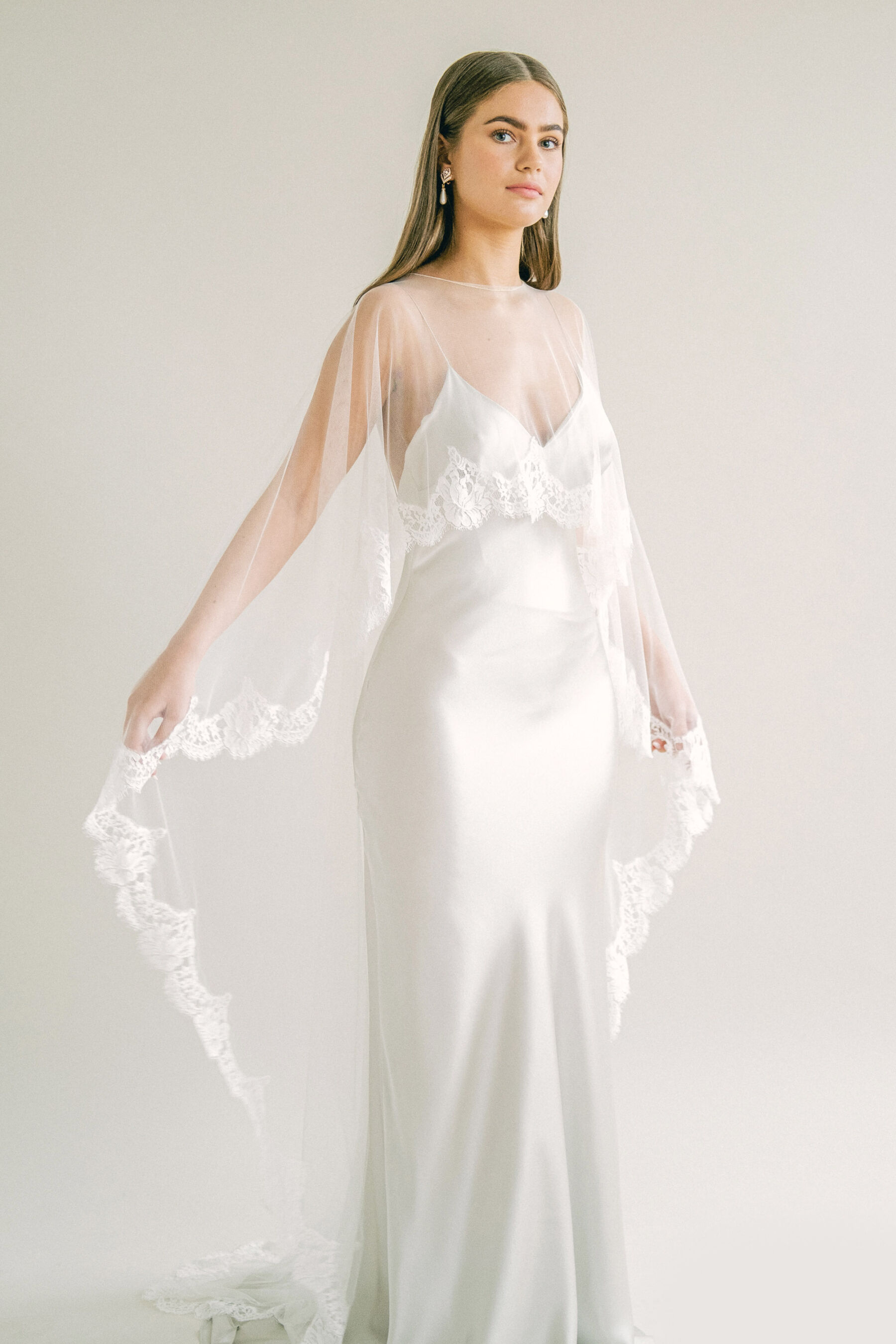 Kate Beaumont wedding bias cut slip wedding dress with cape veil that is shorter at the front and longer at the back.
